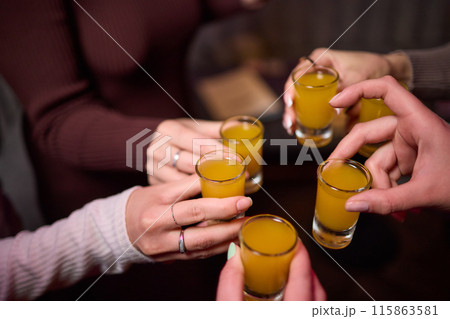 Group cheers with shot glasses of Paulaner hefeweizen wheat beer at fun event 115863581