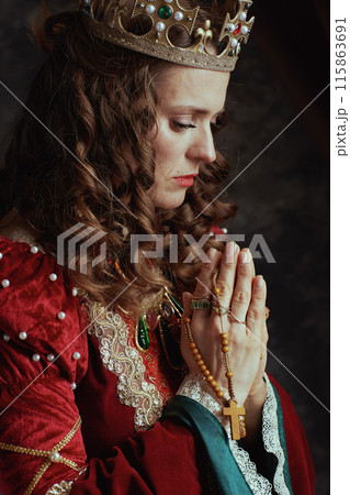 medieval queen in red dress with rosary and crown praying medieval queen in red dress with rosary and crown praying 115863691