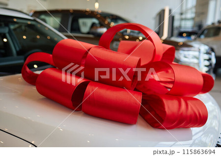 An iconic new car is being presented with a ribbon bow at the showroom for a celebratory event 115863694