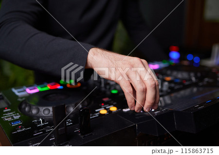 control DJ for mixing music with blurred people dancing at party in nightclub. 115863715