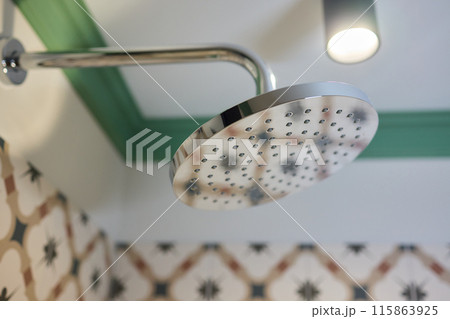 Contemporary stainless steel showerhead in a bathroom, featuring modern design and function 115863925