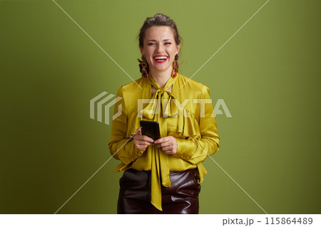 smiling fit woman using smartphone isolated on green background 115864489