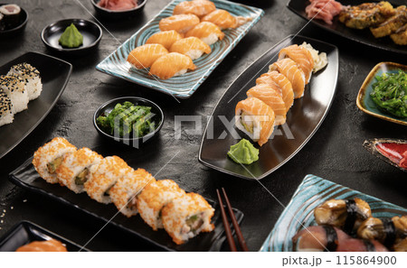 Top view of traditional japanese cuisine . Sushi rolls set with salmon , tuna fish and vegetable served on black stone table . Asian food on black stone slate with chopsticks . Top view of traditional japanese cuisine . Sushi rolls set with salmon , tuna fish and vegetable served on black stone table . Asian food on black stone slate with chopsticks . 115864900
