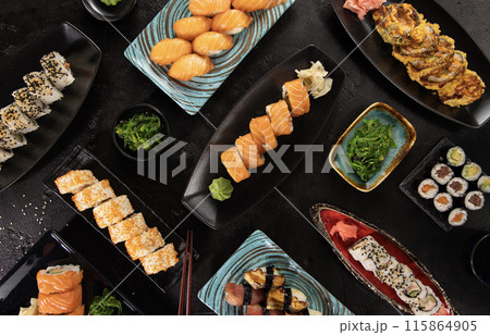Top view of traditional japanese cuisine . Sushi rolls set with salmon , tuna fish and vegetable served on black stone table . Asian food on black stone slate with chopsticks . 115864905