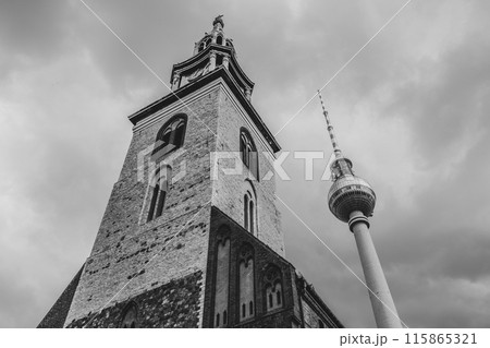 Saint Mary Church stands with the iconic Berlin TV Tower against a dramatic sky. Berlin, Germany. Black and white image.. Black and white image. Saint Mary Church stands with the iconic Berlin TV Tower against a dramatic sky. Berlin, Germany. Black and white image.. Black and white image. 115865321