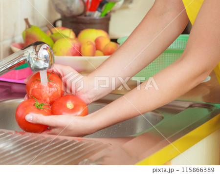 woman washing fresh vegetables in kitchen woman washing fresh vegetables in kitchen 115866389