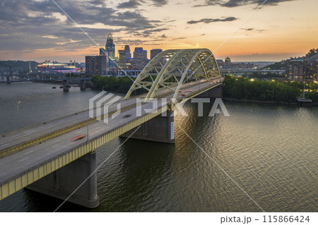 Downtown district of Cincinnati city in Ohio, USA at night with driving cars traffic on Daniel Carter Beard Bridge and brightly illuminated high skyscraper buildings. American travel destination Downtown district of Cincinnati city in Ohio, USA at night with driving cars traffic on Daniel Carter Beard Bridge and brightly illuminated high skyscraper buildings. American travel destination 115866424