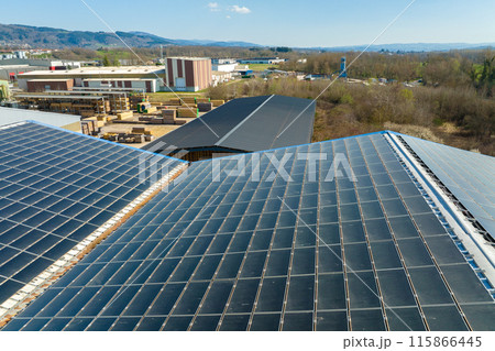 Aerial view of blue photovoltaic solar panels mounted on industrial building roof for producing green ecological electricity. Production of sustainable energy concept 115866445