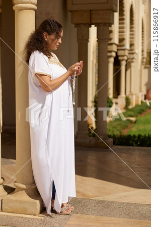 Woman in white traditional dress standing in prayer at historical building Woman in white traditional dress standing in prayer at historical building 115866917
