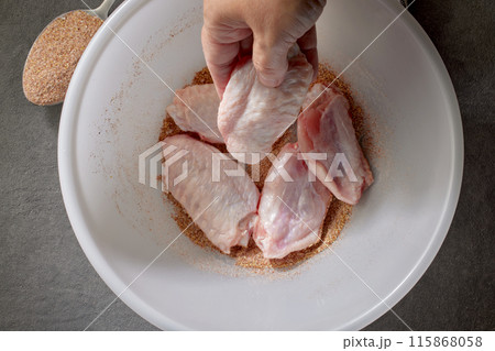 cook put fresh raw chicken wings in bowl of spices 115868058