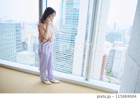 オフィスの窓辺で電話をする女性 115869084