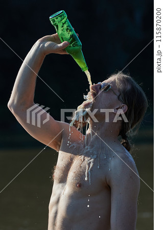 Drinking beer at the beach pouring fast from above 115870200