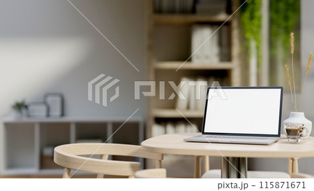A laptop computer with a white-screen mockup on a wooden table in a minimalist room. A laptop computer with a white-screen mockup on a wooden table in a minimalist room. 115871671