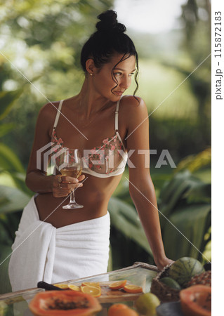 Woman in Lingerie with Wine Glass Relaxing by Tropical Poolside 115872183