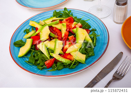 Tasty salad with avocado, tomatoe and arugula at plate 115872431
