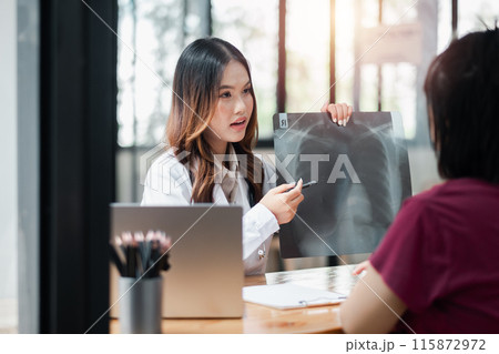 Female doctor discussing X-ray results with a patient in a modern medical office, highlighting professional healthcare and patient care. 115872972