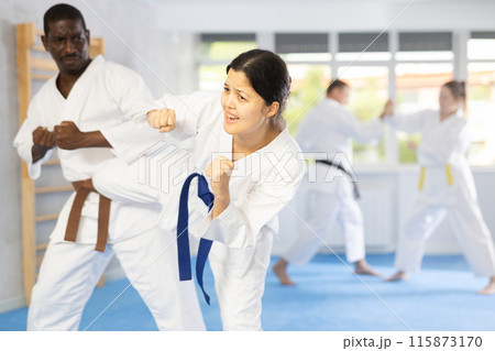 Middle-aged woman attendee of karate classes fighting with her opponent in sports hall 115873170