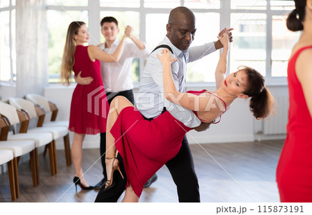 Black man enjoying impassioned merengue with woman in red in studio 115873191