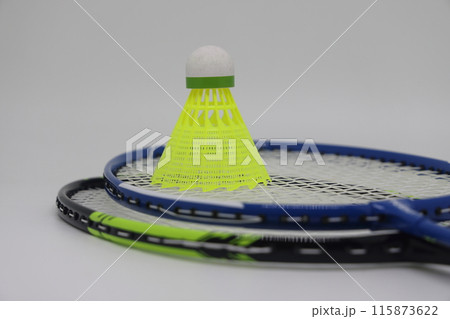 Badminton concept. Badminton rackets and a green shuttlecock on a light background from above. 115873622
