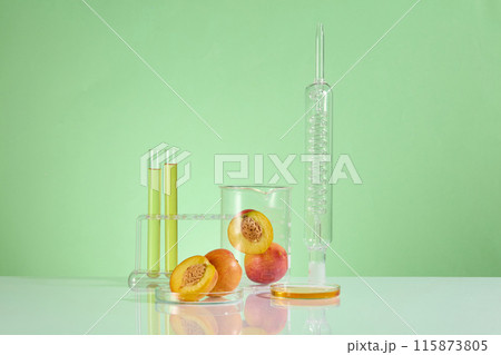 In the center of advertising photo is some experiment glassware including lab condenser, beaker, test tube in rack and petri dish containing a few peaches. Photo has front angle and space for text 115873805