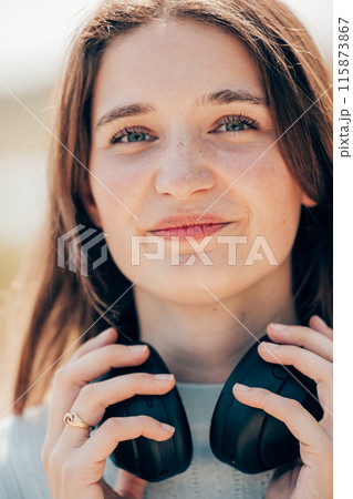 Close-Up of a Young Woman Holding Headphones 115873867