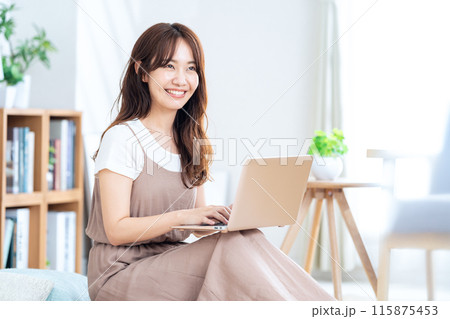 リビングでパソコン見てくつろぐ若い女性 リビングでパソコン見てくつろぐ若い女性 115875453