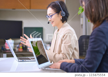オフィスで仕事をするヘッドセットを付けたミドル 115875554