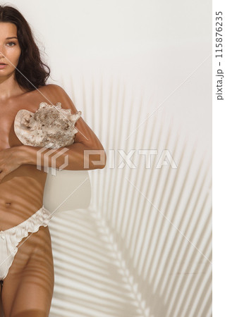Alluring Woman Holding Seashell with Tropical Shadow Play Background 115876235