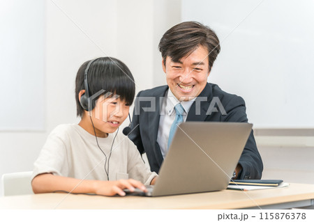学校・塾で個別指導を受ける小学生の子供と先生・教師・家庭教師の男性（スーツ・ビジネスマン） 115876378