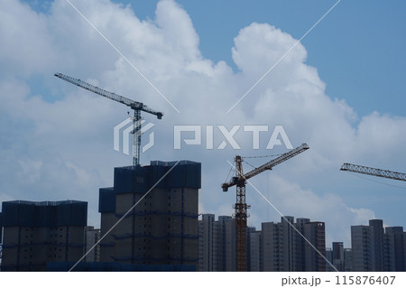 construction site with cranes and building under construction against blue sky 115876407