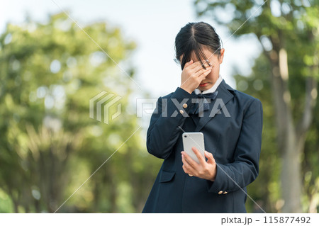 スマホを見ながら泣く・困る・悩む・考える制服姿の女子中学生・女子高校生 115877492