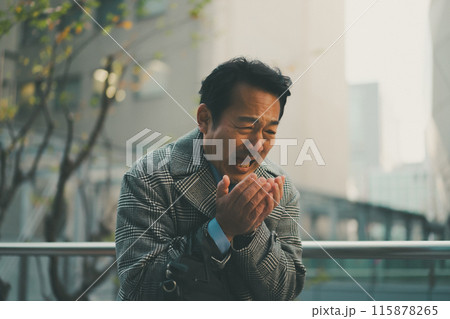 寒さで手に息を吹きかける50代サラリーマン 115878265