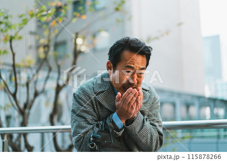 寒さで手に息を吹きかける50代サラリーマン 115878266