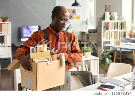 Waist up portrait of senior African American man holding box with personal items at workplace leaving office for late retirement copy space 115878354