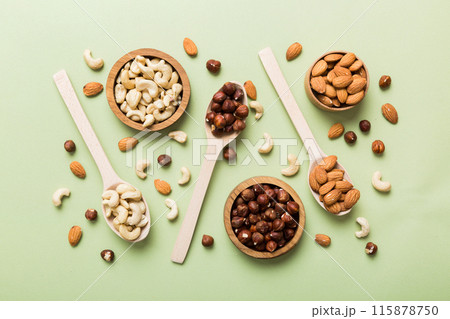 Assortment of nuts in wooden bowl on colored table. Cashew, hazelnuts, walnuts, almonds. Mix of nuts Top view with copy space Assortment of nuts in wooden bowl on colored table. Cashew, hazelnuts, walnuts, almonds. Mix of nuts Top view with copy space 115878750