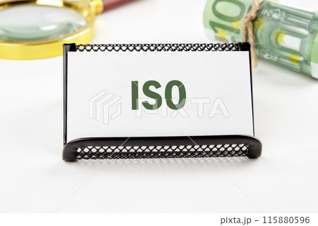 Business and ISO concept. ISO standards quality control symbol. Concept word ISO on a business card in a composition with Euro banknotes and a magnifying glass out of focus 115880596