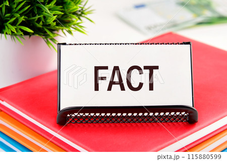 Business concept. FACT word on a business card standing in a stand on a notepad Business concept. FACT word on a business card standing in a stand on a notepad 115880599