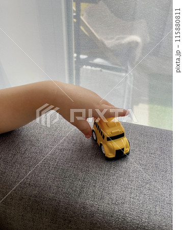 A child's hand is playing with a yellow small toy car 115880811