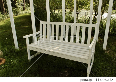 There is a white wooden swing with an arch in the park 115880812