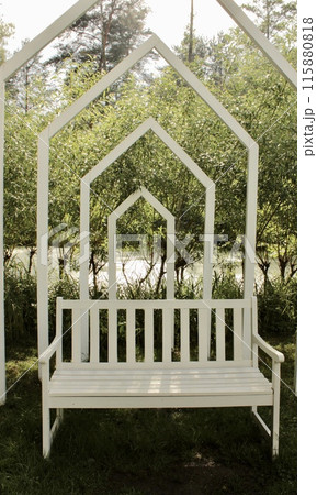 There is a white wooden swing with an arch in the park There is a white wooden swing with an arch in the park 115880818