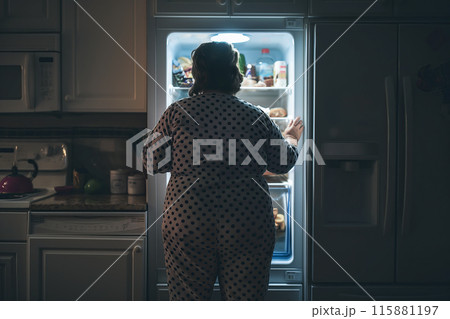 A fat woman stands in front of an open fridge, looking inside. The reflection on healthy eating habits and the relationship between food and body image. Generative AI. 115881197