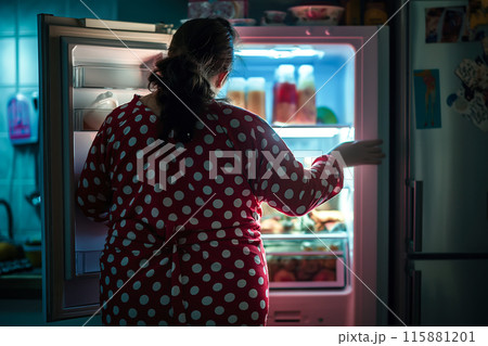 A fat woman stands in front of an open fridge, looking inside. The reflection on healthy eating habits and the relationship between food and body image. Generative AI. 115881201