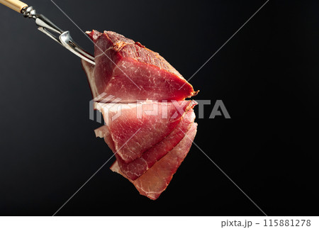 Dry-cured pork fillet on a black background. Dry-cured pork fillet on a black background. 115881278