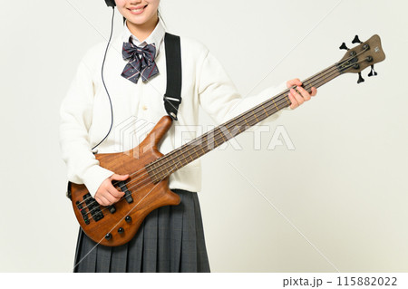 ヘッドフォンをしてベースを弾く女子高生 115882022