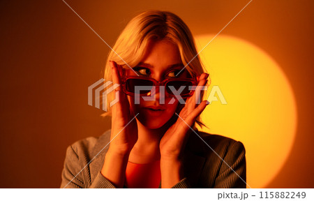 Sunglasses wearing model posing under bright light 115882249