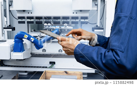 Engineer uses a digital tablet to control robots in a smart factory. Smart industry 4.0 concept. 115882498
