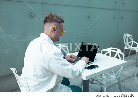 Happy traveling Caucasian man in stylish clothes uses mobile smartphone and laptop, checking trip destination on Internet. Male waiting at flight gates for plane boarding, smiling have a vacation trip 115882520