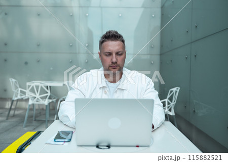 Happy traveling Caucasian man in stylish clothes uses mobile smartphone and laptop, checking trip destination on Internet. Male waiting at flight gates for plane boarding, smiling have a vacation trip 115882521