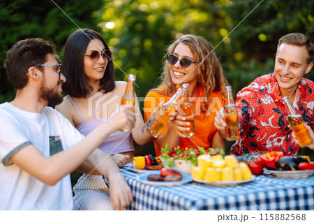 Group of young friends having picnic toasting with beer in nature. Lifestyle, relaxation concept. 115882568