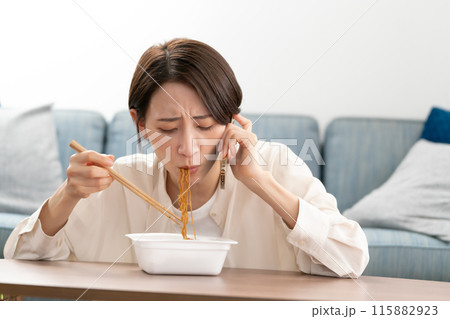 電話をしながら焼きそばを食べるアラフォー女性 電話をしながら焼きそばを食べるアラフォー女性 115882923